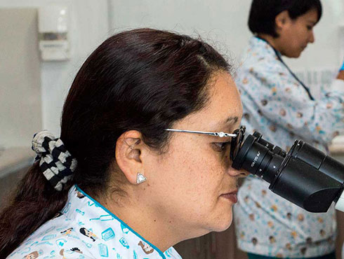 woman looking through microscope