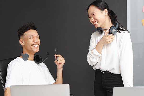 two Asian co-workers laughing