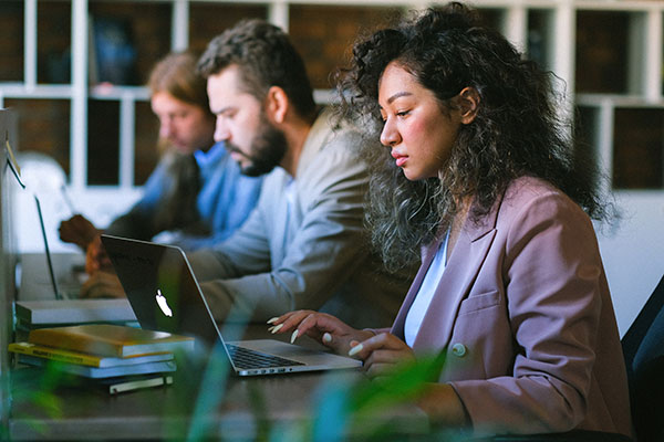 three workers at table on their laptops