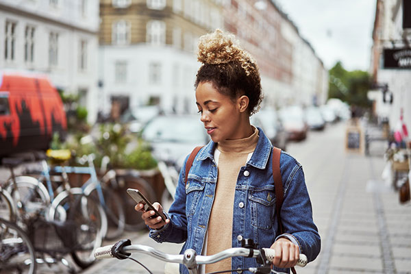 young person looking at cellphone while on bicycle