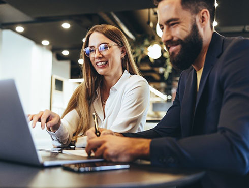 two workers at table with laptop open