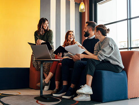 Four people sitting on a couch looking at a laptop