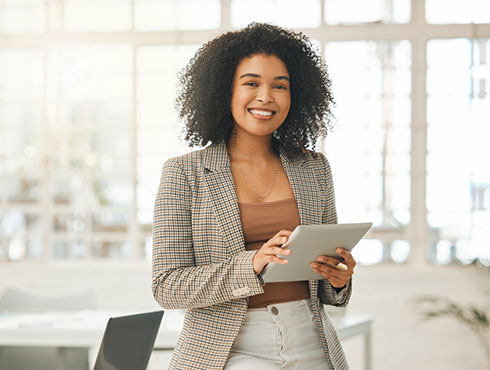 smiling woman holding a tablet in a modern office