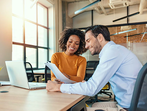 smiling man and woman in an office looking at paper