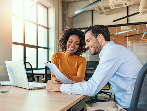 smiling man and woman in an office looking at paper